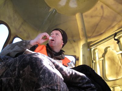 The author survives near blizzard conditions in comfort while enjoying a snack inside a shooting blind during an Iowa deer hunt one December.