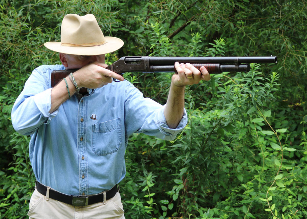 man holding 1897 Winchester pump action 12-gauge