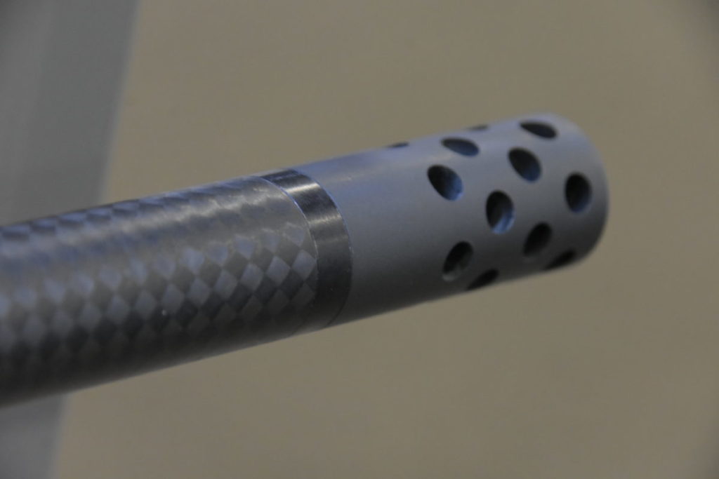 A carbon fiber rifle barrel and attached muzzle brake.