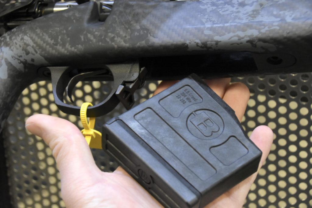 A black rifle magazine lays in a man's hand. 