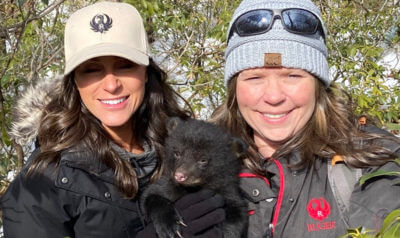 Two women with a bear cub.