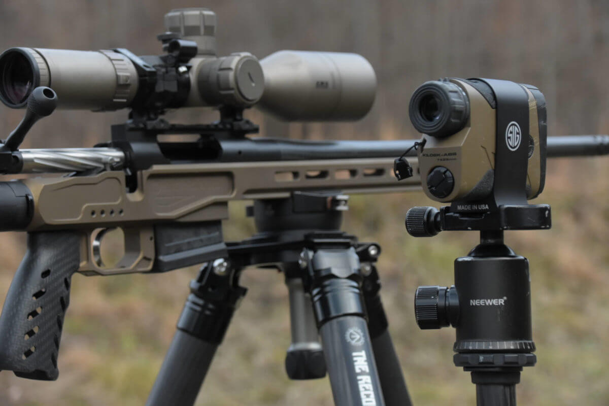 The MgLite sits on a tripod next to a Sig rangefinder at the rifle range.