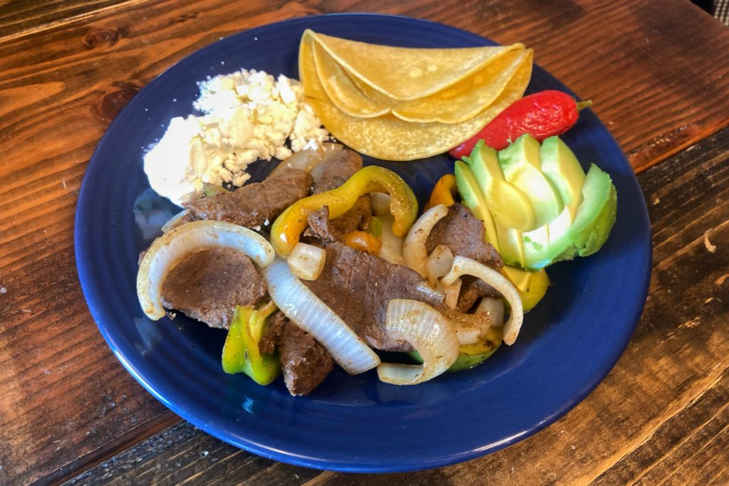 venison fajitas on wooden table with artfully arranged vegetables