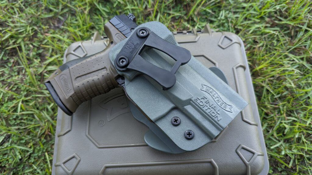 Holstered P99 on carry case resting in the grass