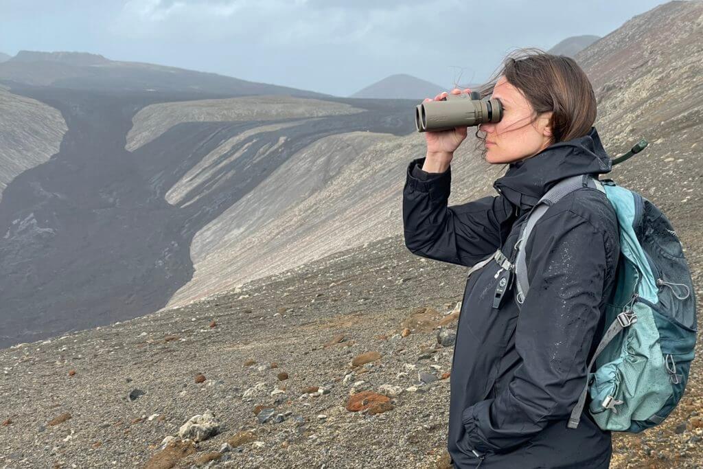 Woman looking out at lava flows through Sig Sauer binoculars