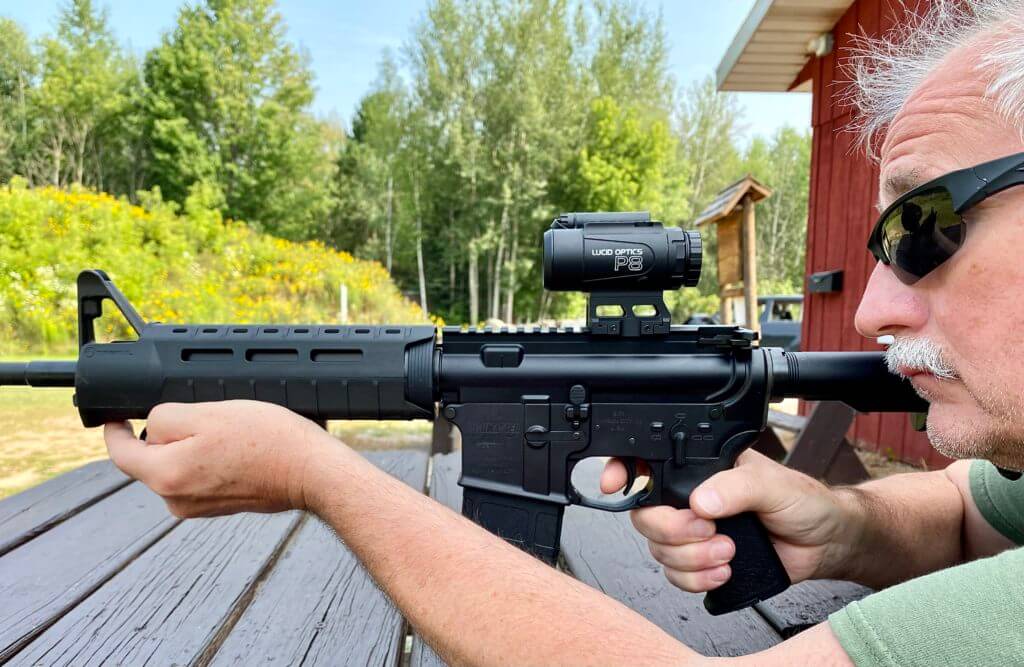 Man in sunglasses shooting an AR-15 with the Lucid Optics P8 4x