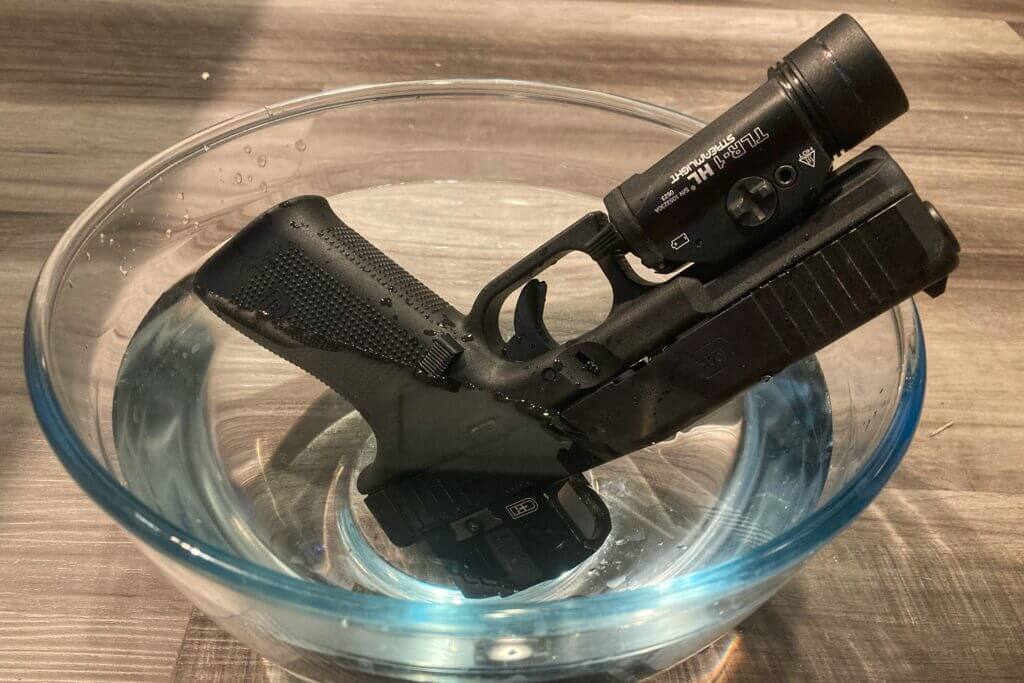 firearm with optic in bowl of water running waterproof test