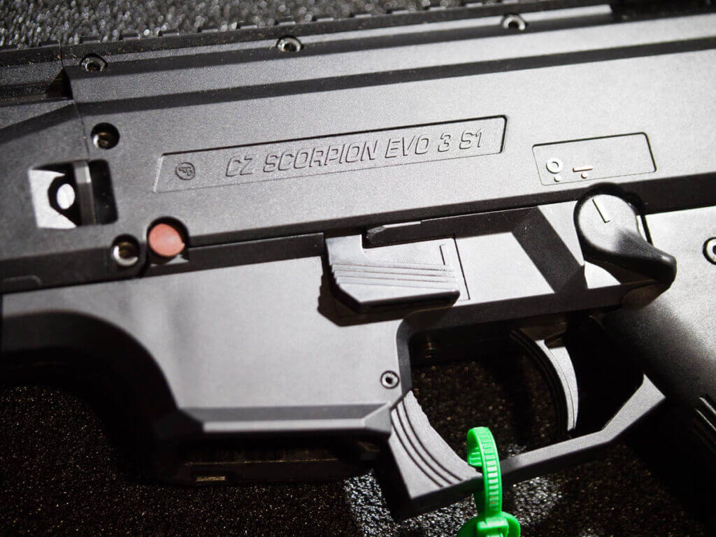 Close up view of the fire control area whoins the trigger, the magazine release, and the safety selector. The gun is pointed to the left.