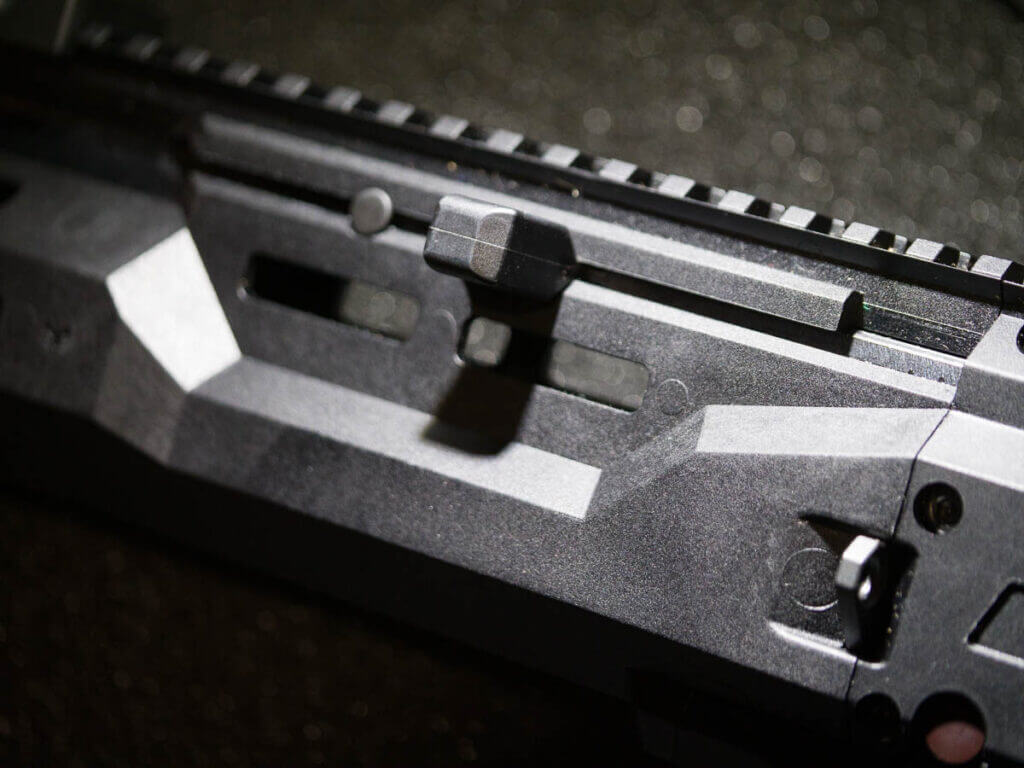 close up of the charging handle in the fore stock. The gun is facing left.