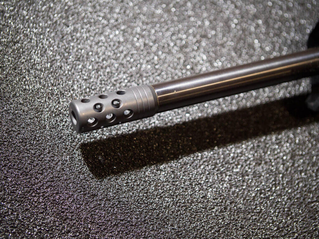 Close up view of the end of the barrel with a radially ported muzzle brake.
