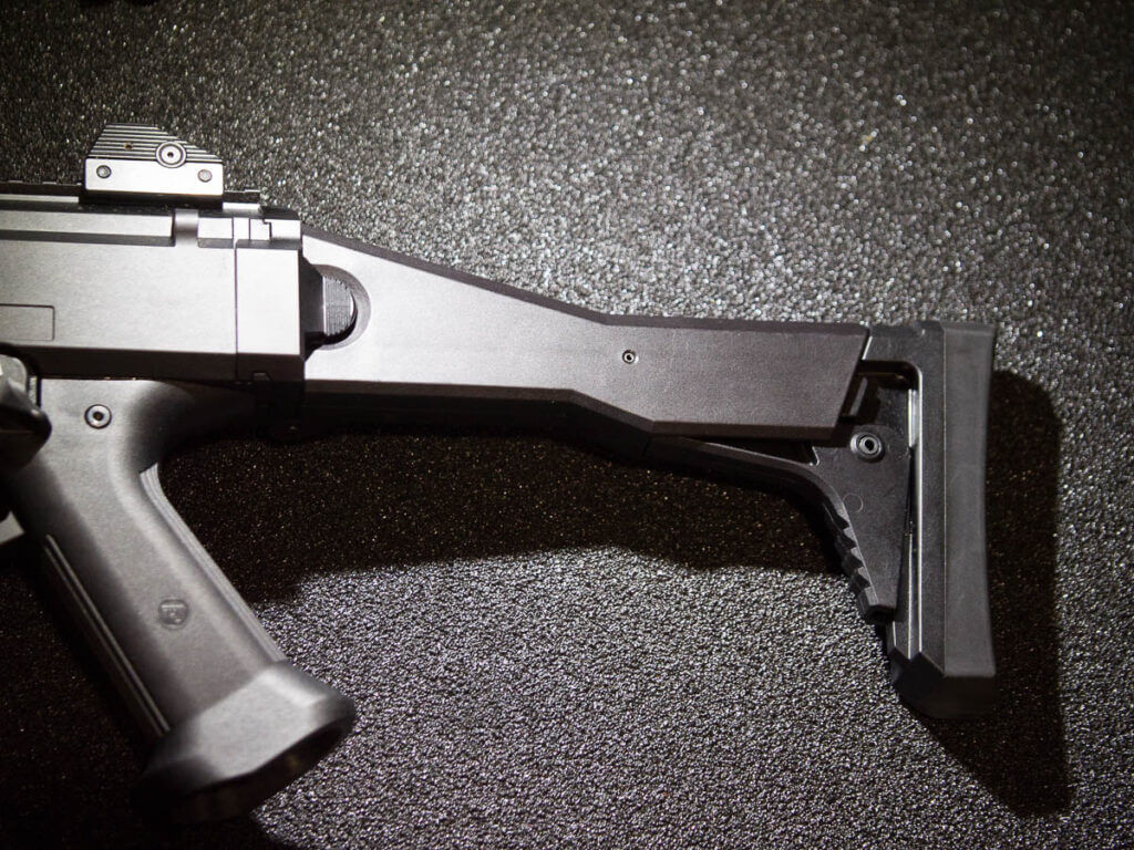 Close up photo showing the back end of the gun including the grip and the butt stock. The gun is pointing to the left.