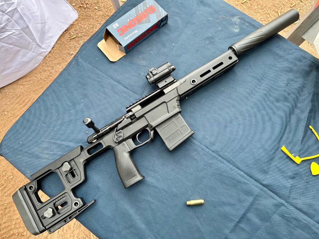 A black rifle lays posed on a blue table at the gun range.