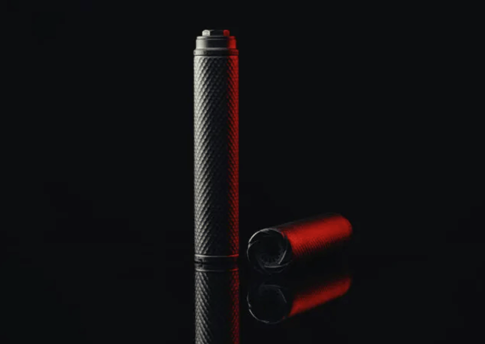 A suppressor sits on a black mirrored surface with red glow being emitted from the side.