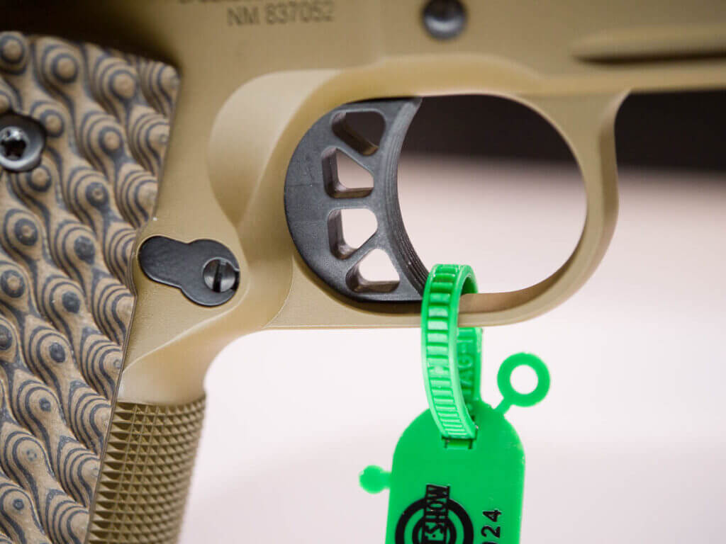 Close up view of the trigger. The coyote brown gun is pointed right. The trigger has four triangular cutouts.