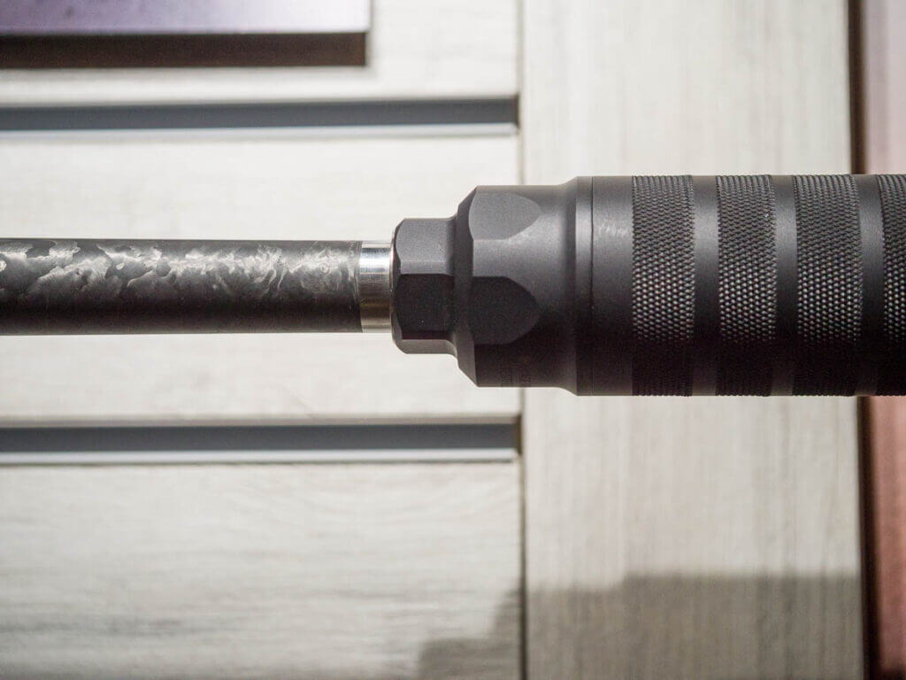 Close up of the end of the barrel with a suppressor attached.