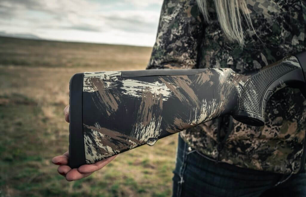 Shotgun butt stock next to woman in camo jacket