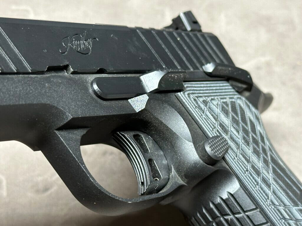 A close look at the trigger on a black Kimber KDS9C handgun.