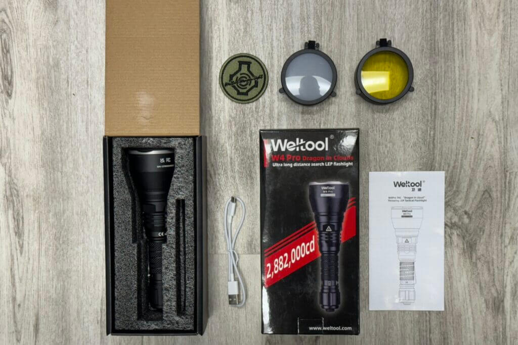 Unboxing the Weltool W4Pro Tac flashlight on a wooden table