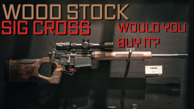 A SIG Cross rifle with wood furniture hanging on a wall.