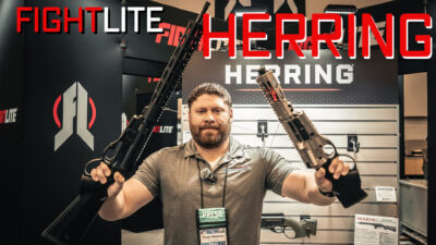 True holding out a FightLite Herring lever-action AR rifle.