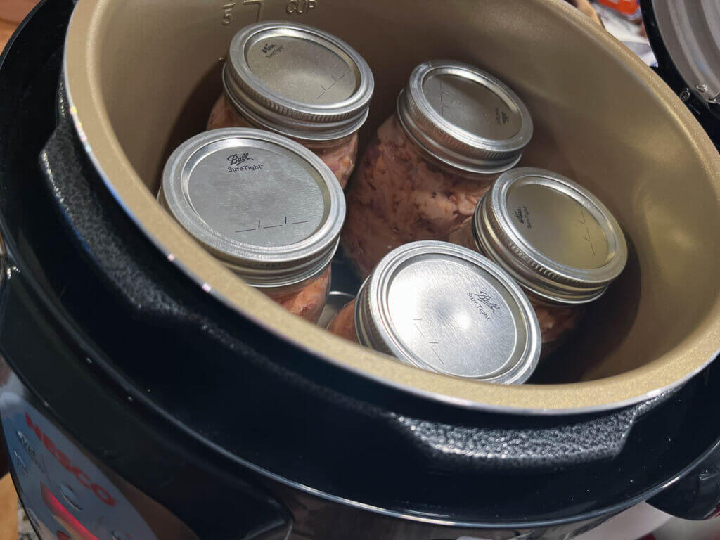 Nesco Canner with five pint jars inside.