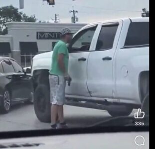 Man approaches truck with gun in hand.