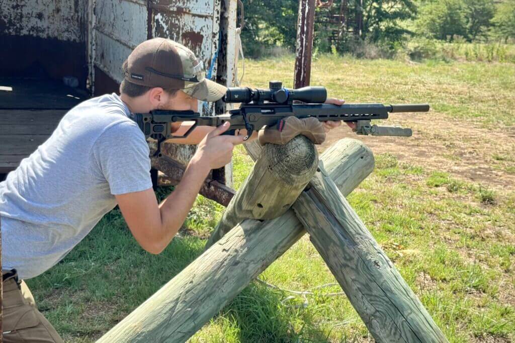 Man shooting the Christensen Arms MPR Rimfire against a wooden post