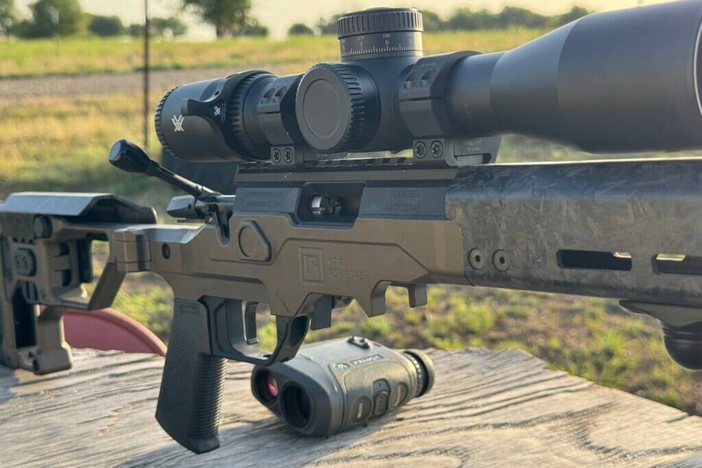 bolt action rifle on wooden table with range finder