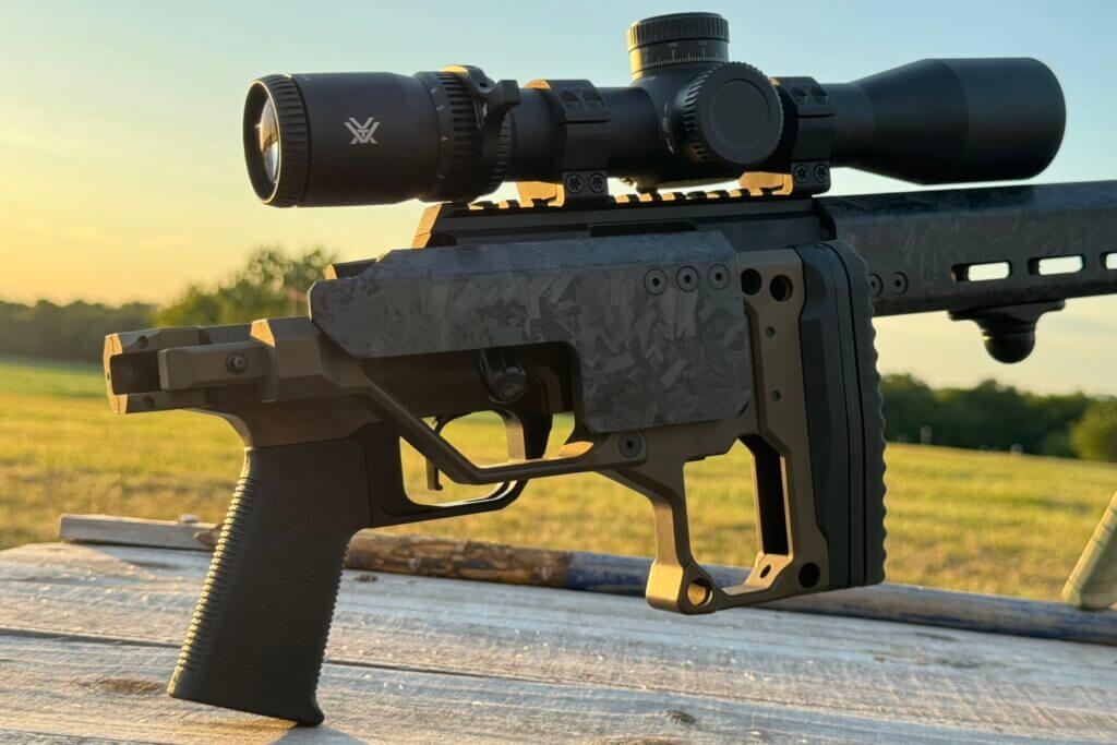 rifle folding stock on wooden table in front of yellow sunrise