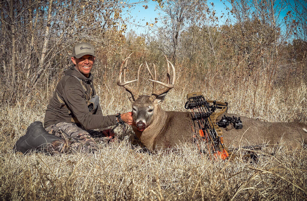 Hunter in tall grass with deer and bow