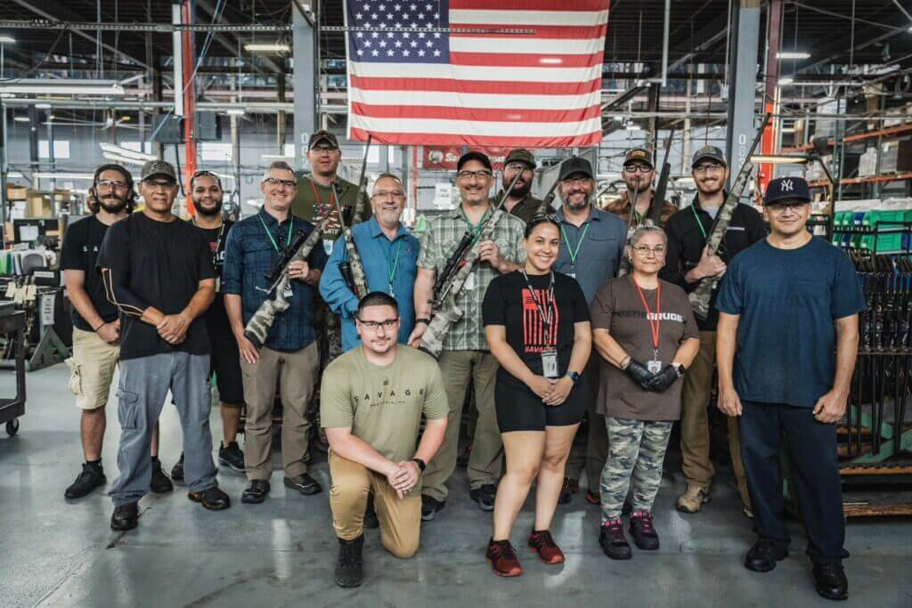 Group of people holding guns in front of United States flag