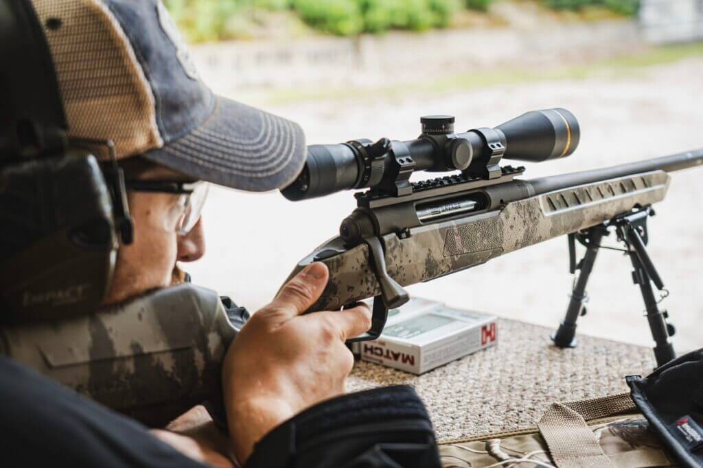 Shooter aiming Savage AXIS 2 Pro with riflescope at range