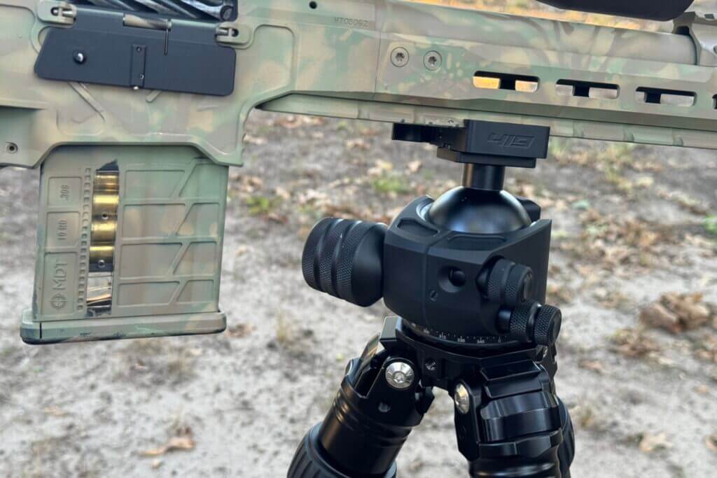 Camo rifle on black tripod