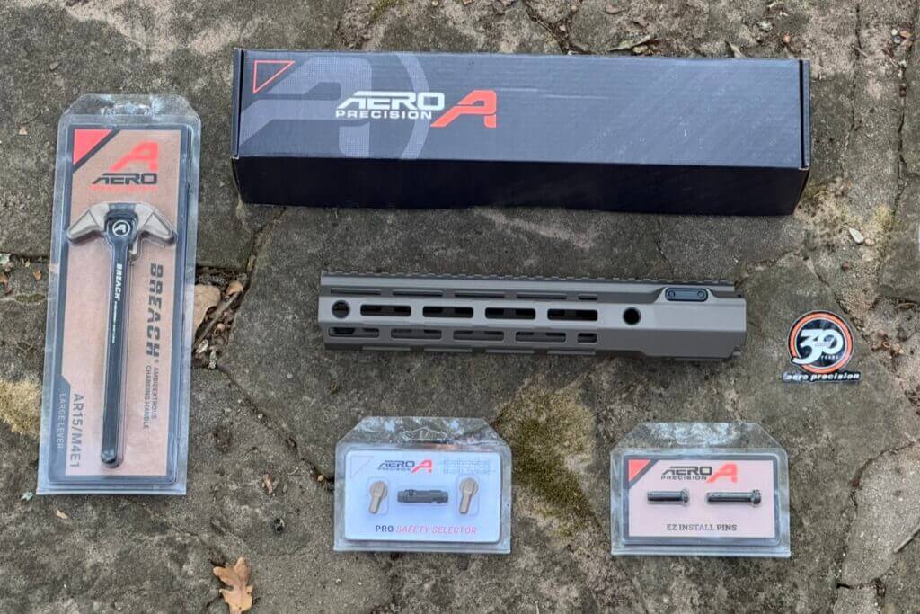 Aero Precision new AR charge handle hand guard safety set laid out on stone ground