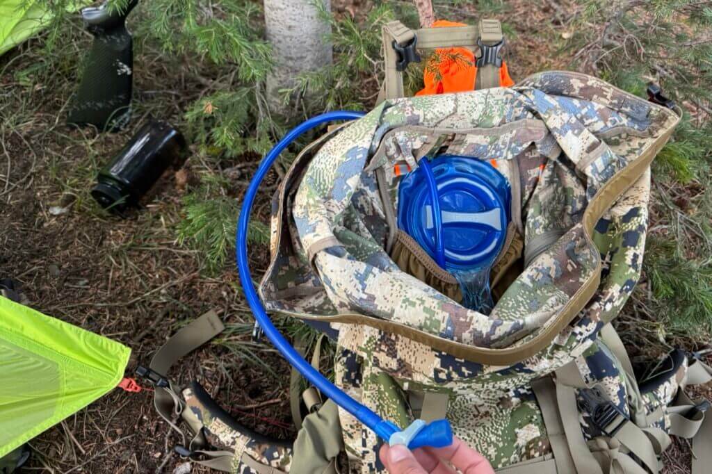 Insert for securely holding a water bladder and running the hose through the back of the pack