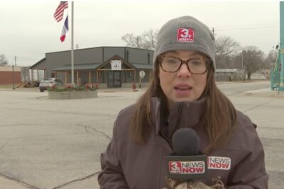 Female reporter in the front of a deer processing store.