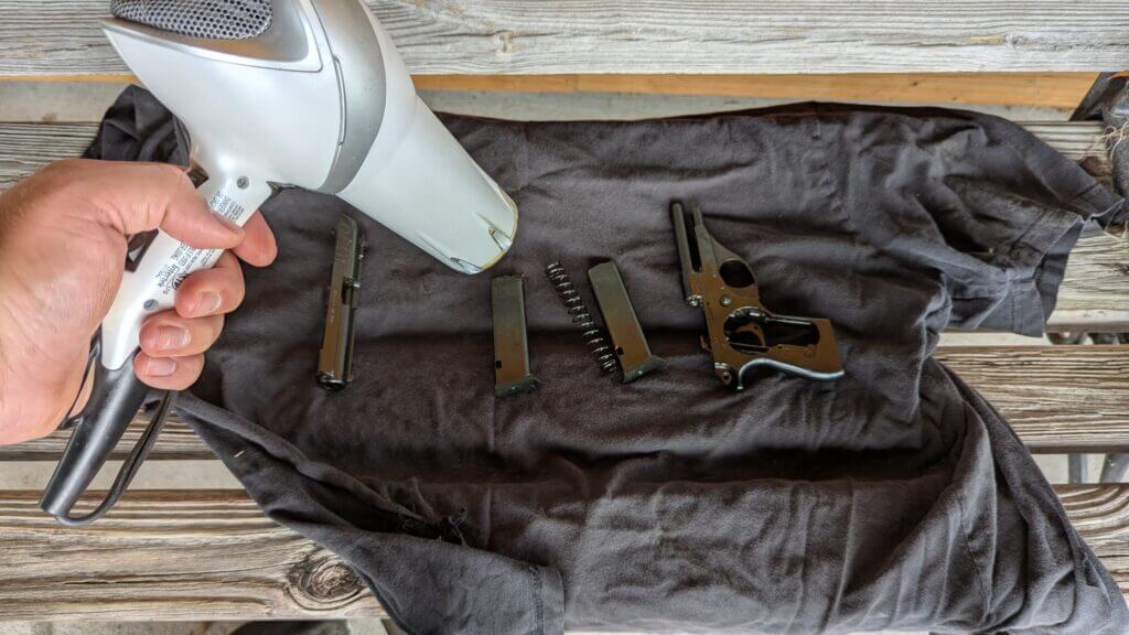 hair blow dryer pointed at gun parts on old towel