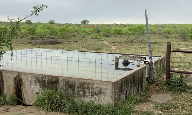 a cistern full of water near a pasture