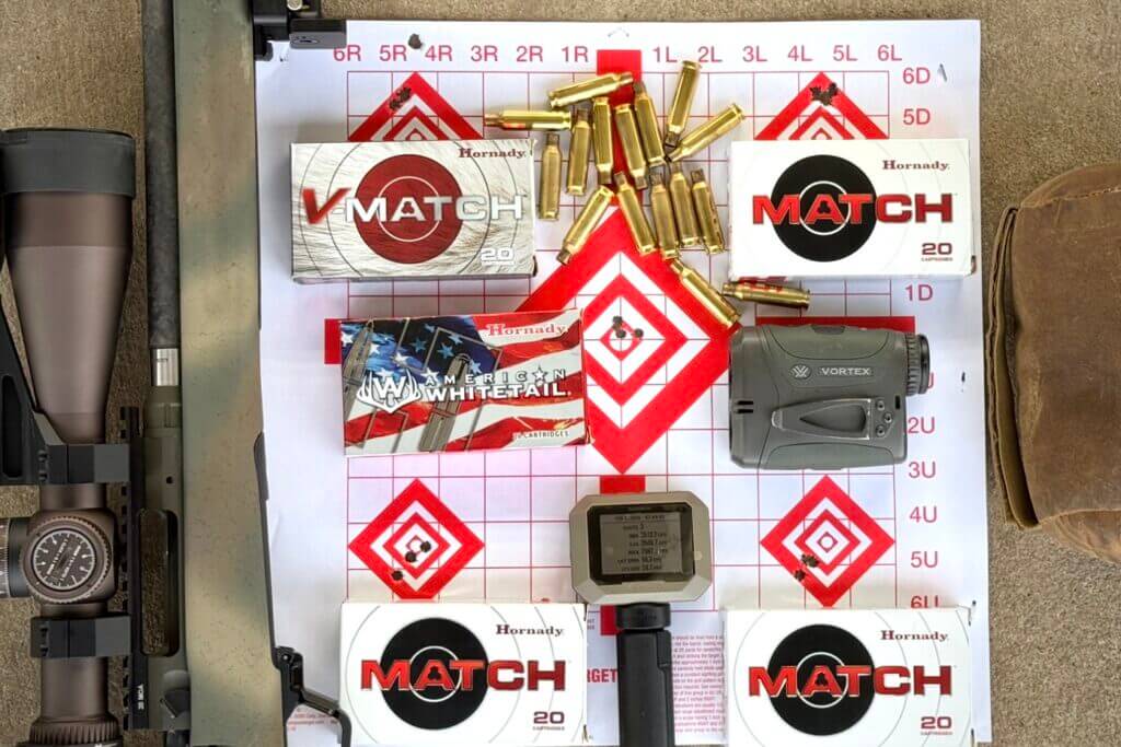 Hornady ammo on paper target with used brass ammo casing and rangefinder