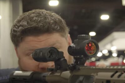 True putting his eye to a Trijicon MRO red dot.