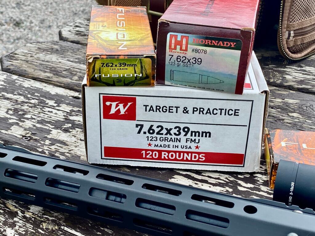 boxes of ammo near a rifle on a table