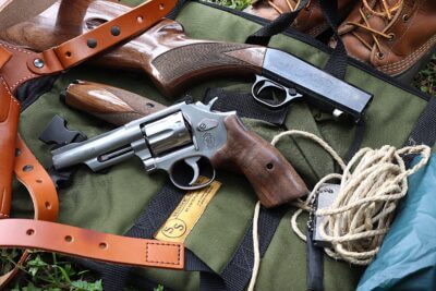 smith & wesson 617 mountain gun with a browning sa-22, rope, flint striker, holster, and poncho