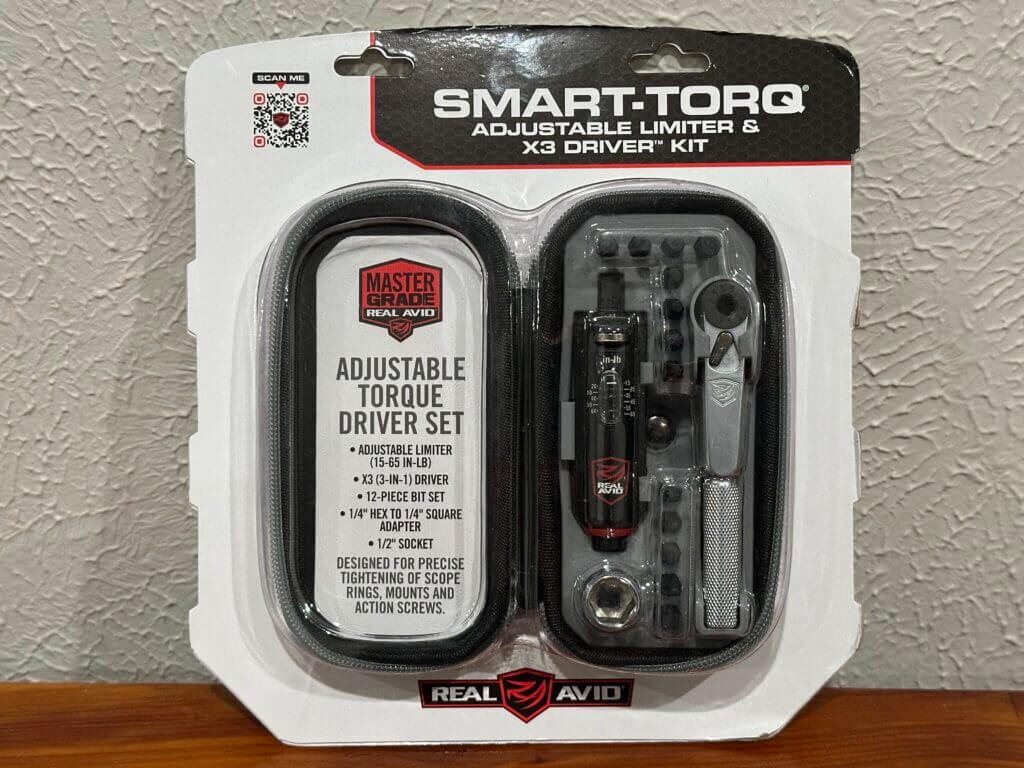 The packaged wrench set sits on a wooden bench against a white wall.