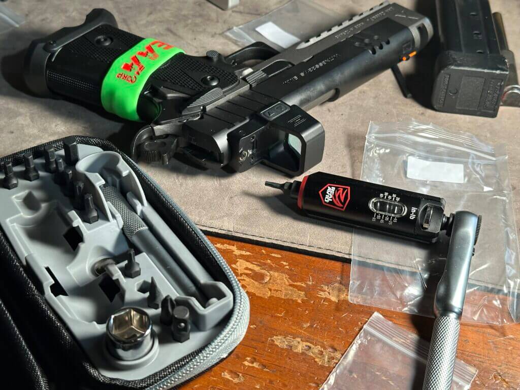 A Smart-Torq wrench lays next to a pistol with a freshly-installed red dot optic. 
