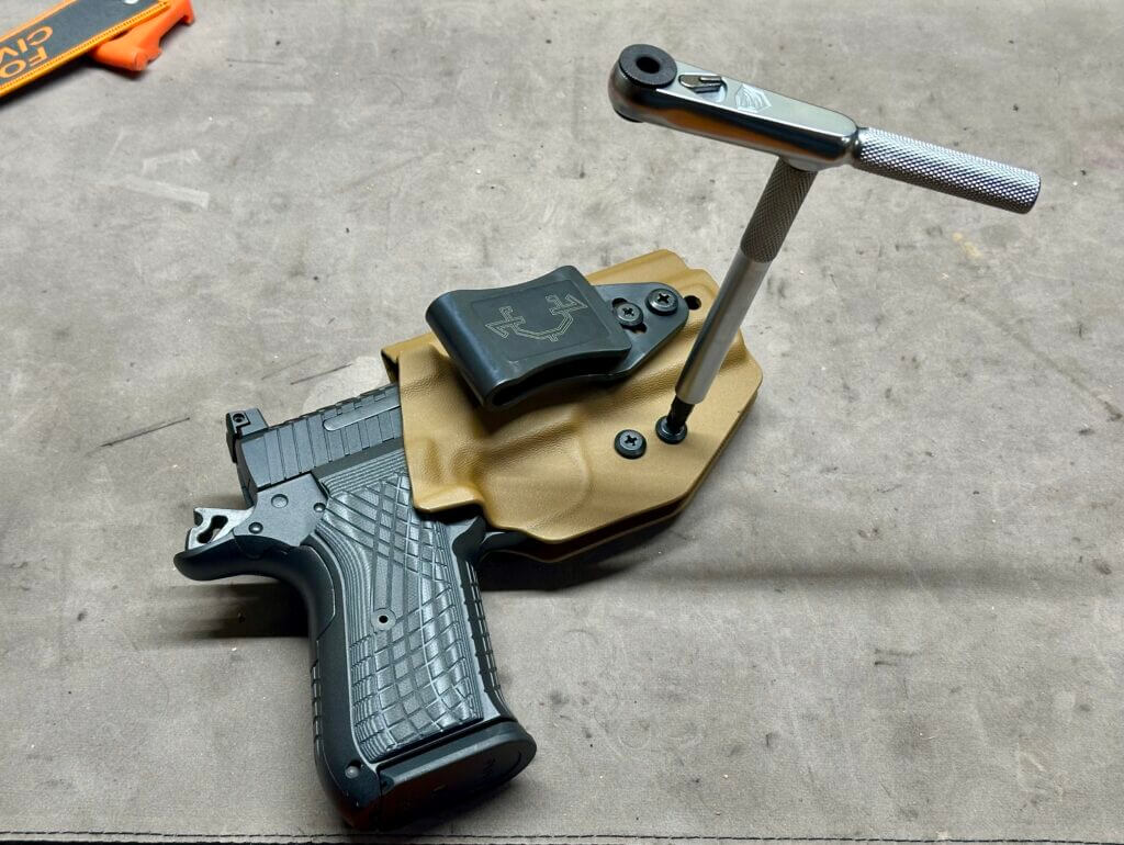Using a T-handle wrench to tighten a brown pistol holster's retention screws. 