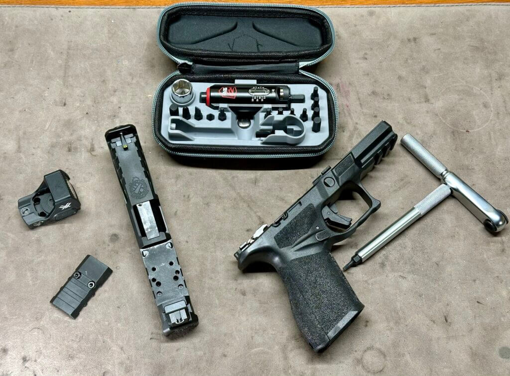 A disassembled pistol lays on a mat where it is being worked on with the Smart-Torq wrench and driver laying next to it.