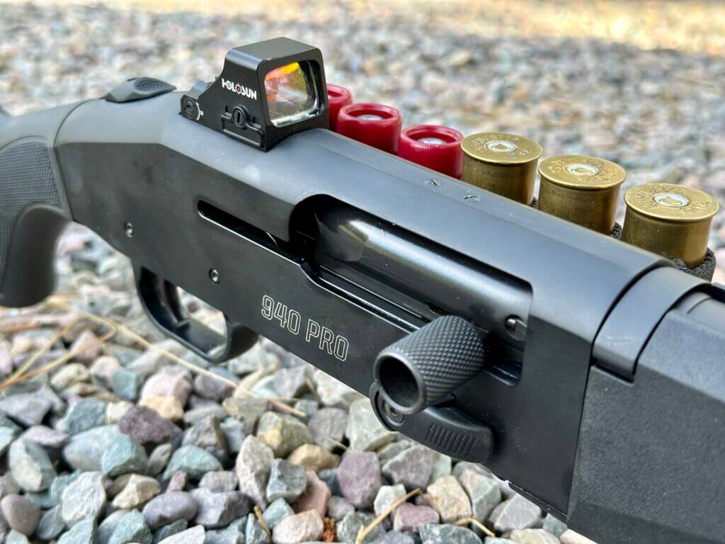 Closeup of a semi-auto shotgun reveiver and a red-dot.
