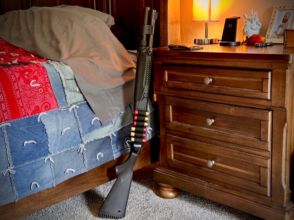 The 940 Pro Tactical SPX is propped up between a black walnut bed and nightstand.