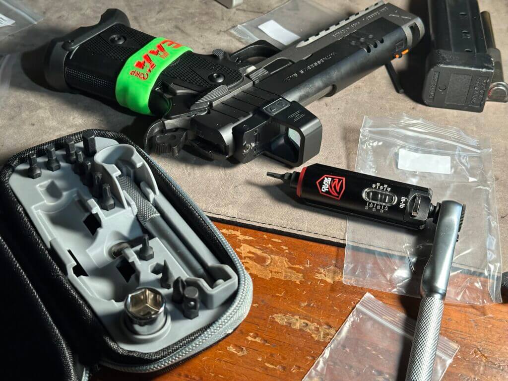 A handgun and tool set are laid out on a work bench. Witness2311 Match X