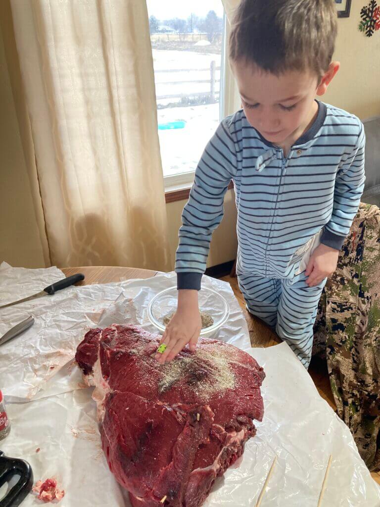 Seasoning whole rear elk quarter heavily for smoking on Traeger